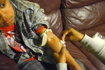 Marcy Perrin's son, Archie, 8, has hemophilia. She must give him injections of life-saving medicine three times a week.  Here, she demonstrates how she finds his vein.