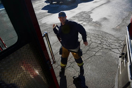 After receiving the call about sparking wires, firefighter Dan Reiser puts on his gear in the parking lot. When the firefighters return later to the grocery store, their cart is still there.