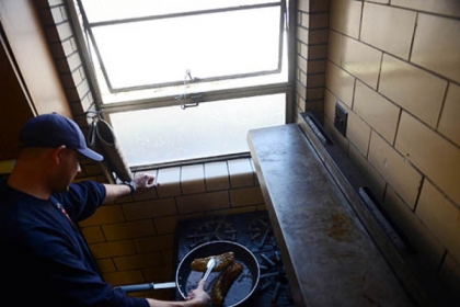 Firefighter Dan Reiser prepares pork for the station's Cuban sandwiches on Friday, Jan. 18, 2013.  Station 17 would receive and respond to three calls during the meal preparation, leaving the food unready each time.