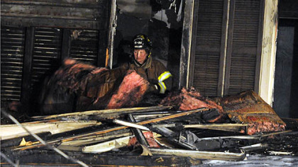 A firefighter removes debris from the burned home in Carrick.