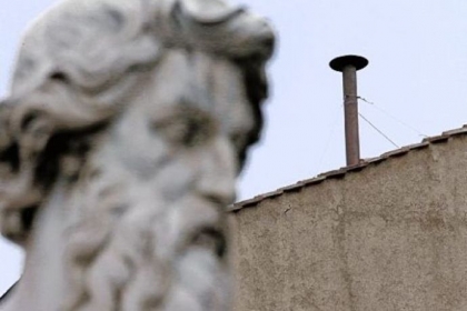 A statue dwarfs the chimney on the roof of the Sistine Chapel, where cardinals will gather today to elect the new pope during the conclave at the Vatican.