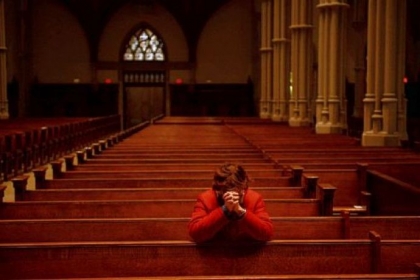 A woman kneels to pray Wednesday for Pope Francis at St. Paul Cathedral in Oakland.