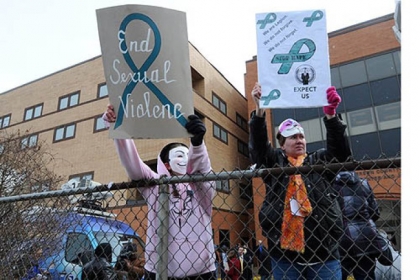Demonstrators wearing Guy Fawkes masks wave their signs at passing traffic outside the Jefferson County Justice Center, where the rape trial for two juveniles is being held in Steubenville, Ohio.