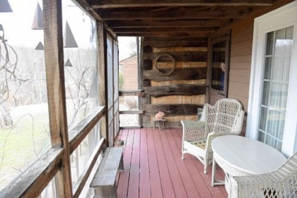 The screened-in porch offers views of a garden.