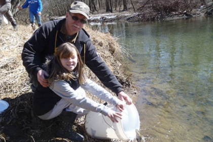 Makayla Boda, 9, and her grandfather Carl Dranzo of Roscoe stock trout at Loyalhanna Creek.