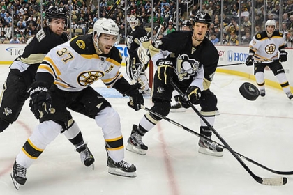Penguins defensemen Mark Eaton, right, and Matt Niskanen, left, tie up the Bruins' Patrice Bergeron.