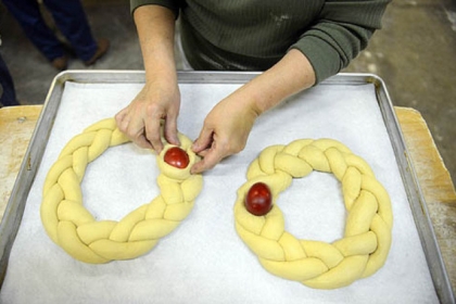 Renie Wadding of Aliquippa places eggs into dough as members of the ladies' group Philoptochos from Kimis Tis Theotokou Greek Orthodox Church of Aliquippa make "tsoureki," a braided sweet Easter bread, at Mediterra Bakehouse in Robinson.