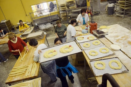 Silvia Kazas of Beaver carries a tray ready for baking as members of the ladies' group Philoptochos from Kimisis Tis Theotokou Greek Orthodox Church of Aliquippa make tsoureki, a braided sweet Easter bread, at Mediterra Bakehouse in Robinson.