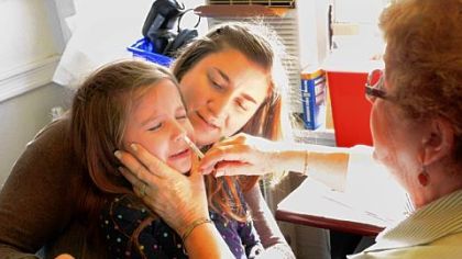 Eva Huckle, 5, of the South Side, receives a flu mist Tuesday from registered nurse Gretchen Balestreire at the Department of Health in Oakland. Eva's mom, Carrie Huckle, 35, offers comfort.