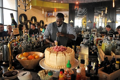 Bartender Cecil Usher mixes drinks for the packed brunch crowd at Meat and Potatoes, Downtown.  The cake in front of him is a peanut butter-raspberry jam cake.