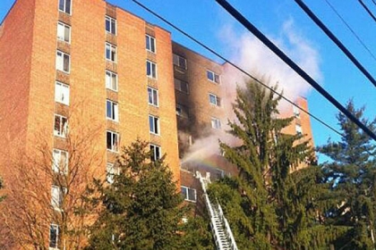 Smoke pours from the building as crews battle the fire this morning in the nine-story Amberson apartment complex on Bayard Road. A man died in the fire.