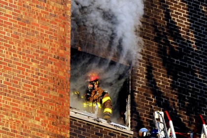 A Pittsburgh firefighter comes to a fifth floor window at the Amberson Apartments in Shadyside.