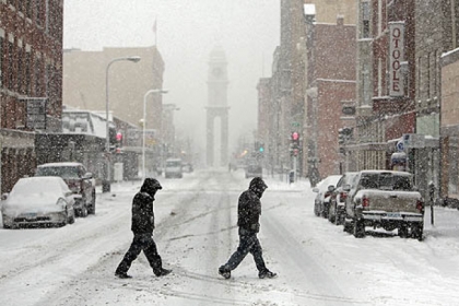 Pedestrians cross Main Street in Dubuque, Iowa during heavy snow today. The storm is headed toward western Pennsylvania.