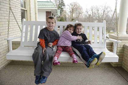 Ben, 7, Maria, 4, and Sam McAuley, 5, rock in the swing on their new front porch in Mt. Lebanon.